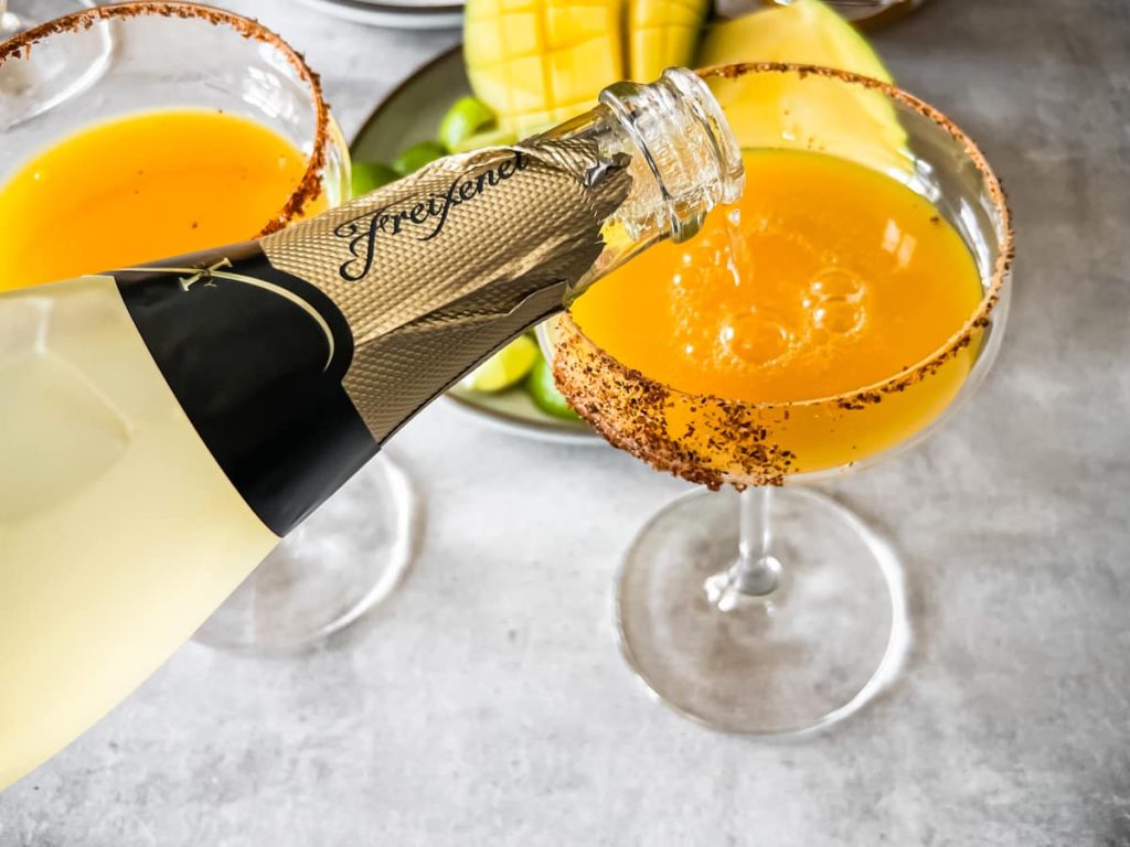 Mango Mimosa – en frisk og tropisk cocktail, der kombinerer den søde smag af mango med den lette og boblende tekstur fra champagne, perfekt til brunch eller festlige lejligheder.