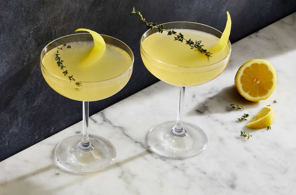 Bees Knees cocktail serveret i et coupeglas med citronskal som garnish – en klassisk drink med gin, honning og citron.
