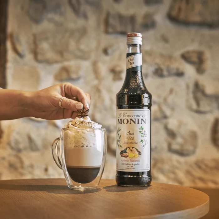 Coco Chai drink serveret i et glas med isterninger og drysset med krydderier – en forfriskende kombination af kokos og chai med tropisk twist.