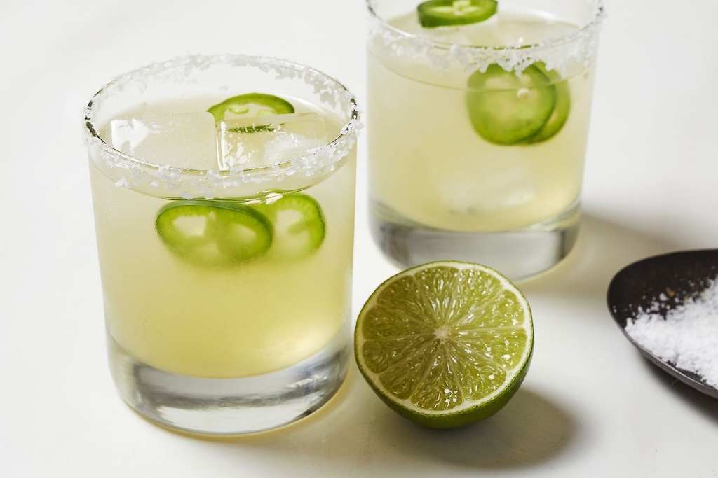 Spicy Jalapeño Margarita serveret i et lowballglas med isterninger, grøn jalapeñoskive og lime – en frisk og stærk twist på den klassiske margarita.