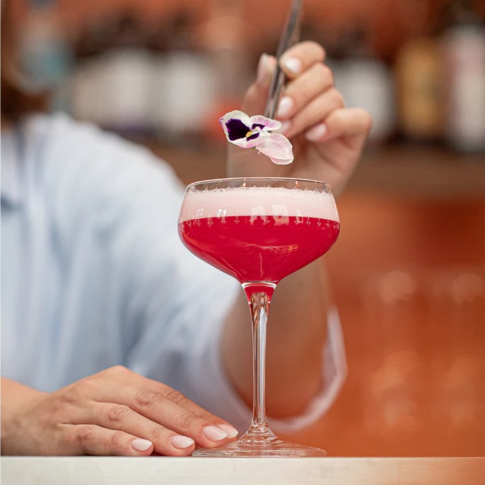 Victoria Club cocktail i coupeglas, præsenteret med en klar lyserød farve og elegant garnering – en feminin og festlig drink.